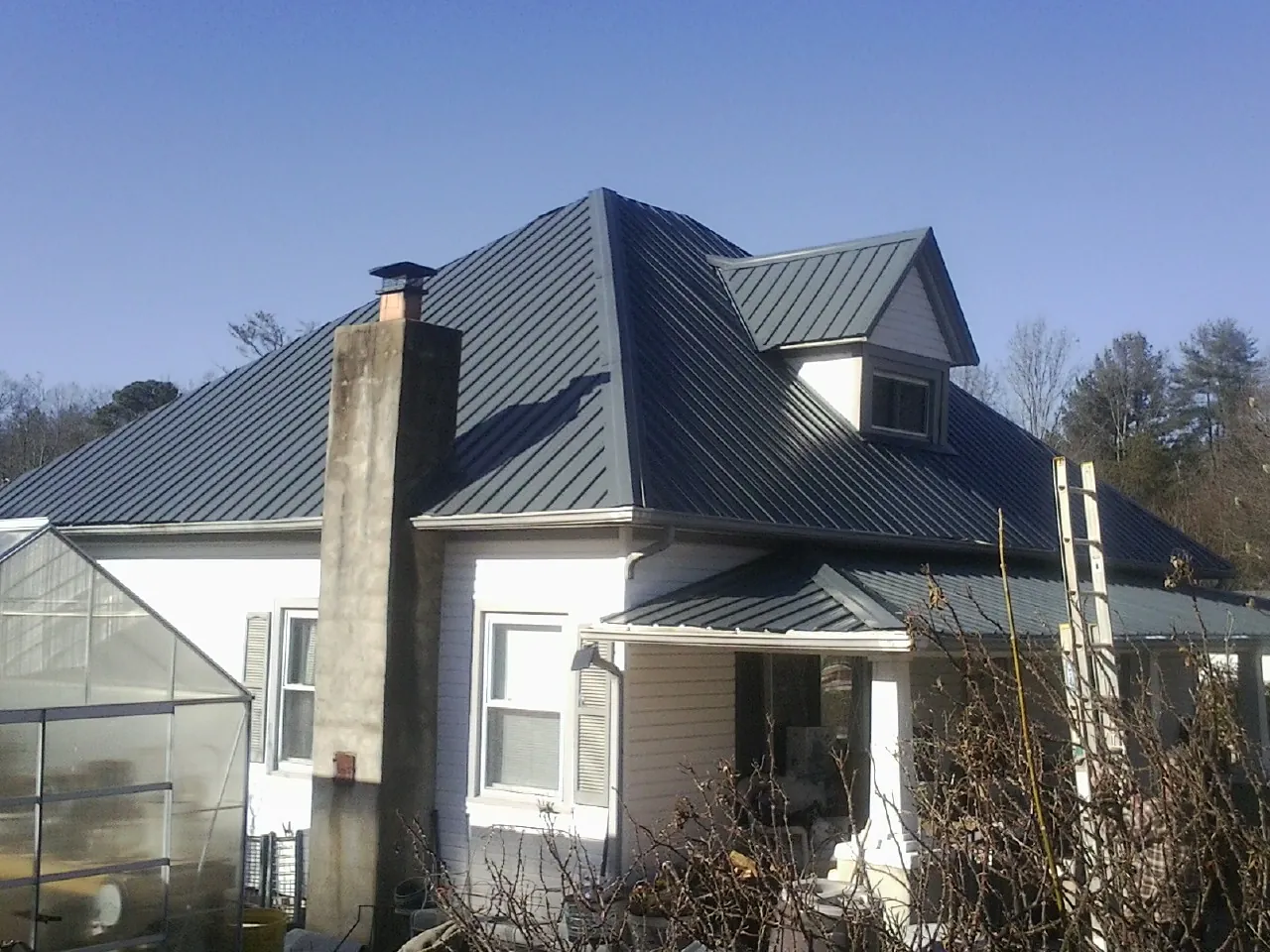 Dark blue standing seam metal roof on a white farmhouse with dormer — Slate & Tile Roof Repair by Roofing Brothers in Pinopolis