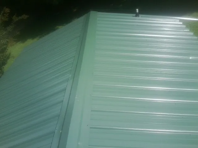 New green metal panels meeting at the ridge of a roof — Flat Roof Repair work by our crew in Pinopolis