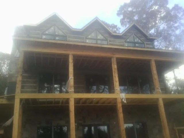 Dormers and porch framing on a large log home under construction — Roof Coating work by our crew in Pinopolis