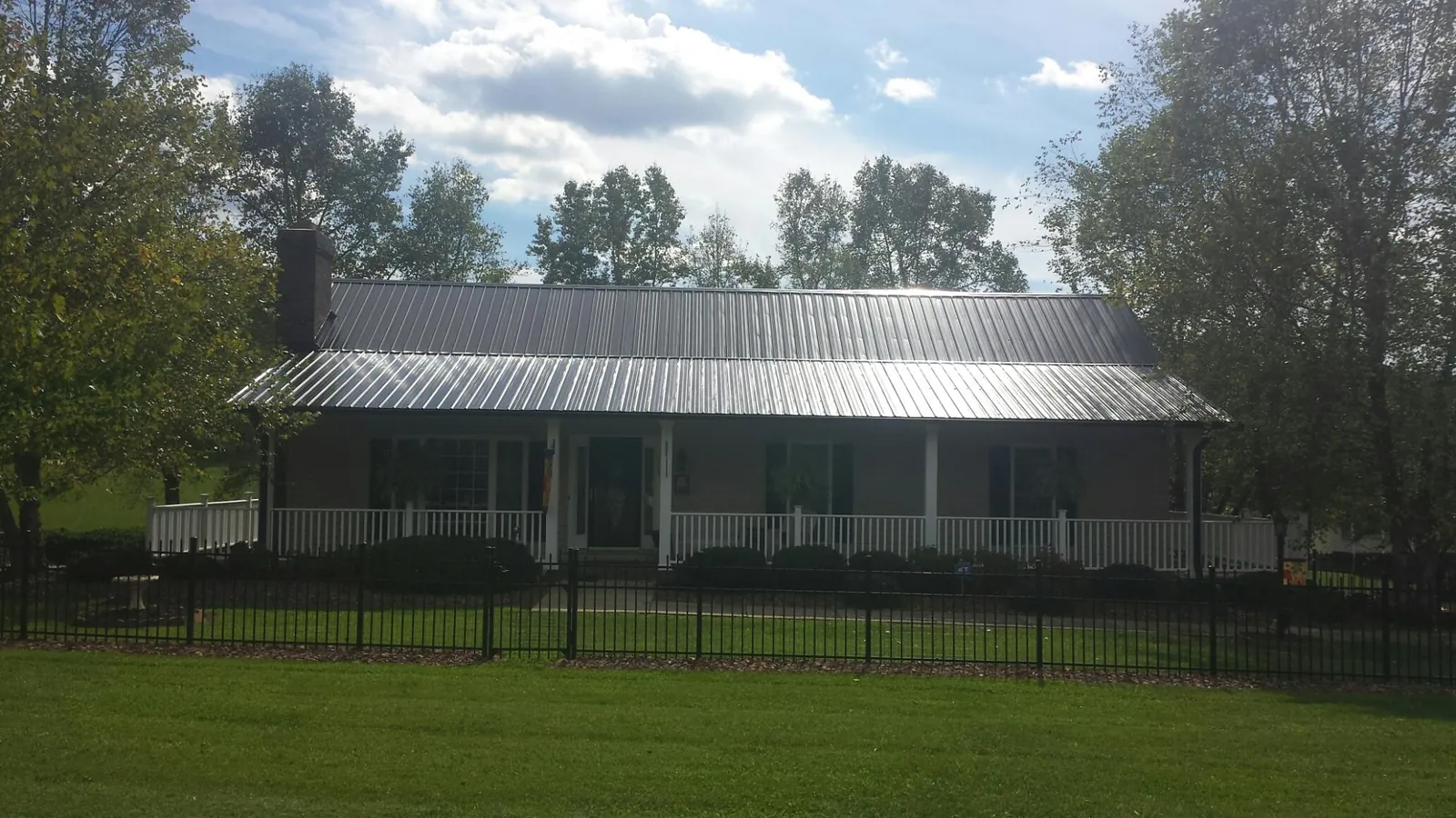 Gray metal roof on a brick ranch with a full width front porch — Gutter Guard Installation work by our crew in Pinopolis