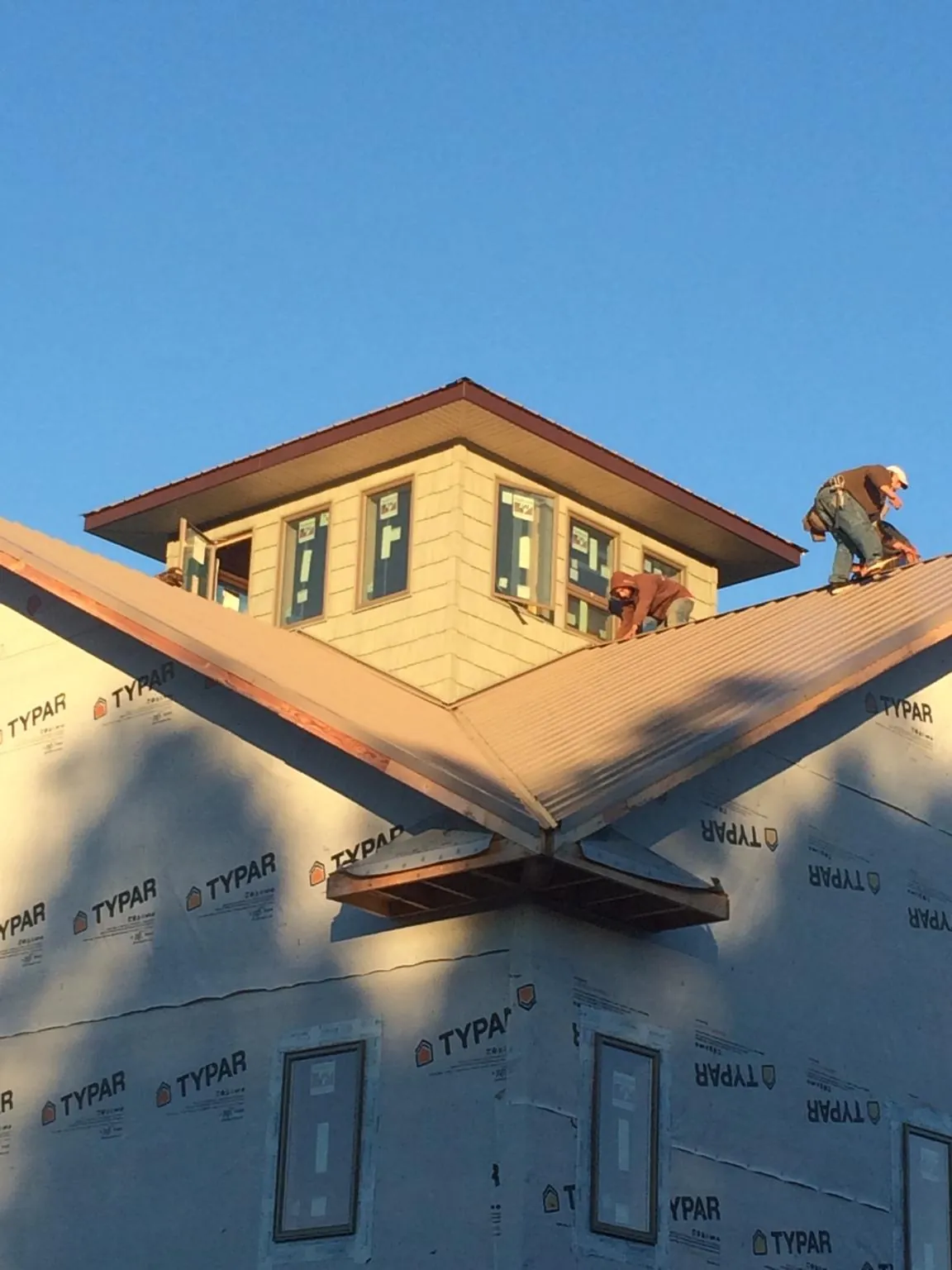 Roofers working around a rooftop cupola on a new metal roof at sunset — Roof Waterproofing in Pinopolis by Roofing Brothers